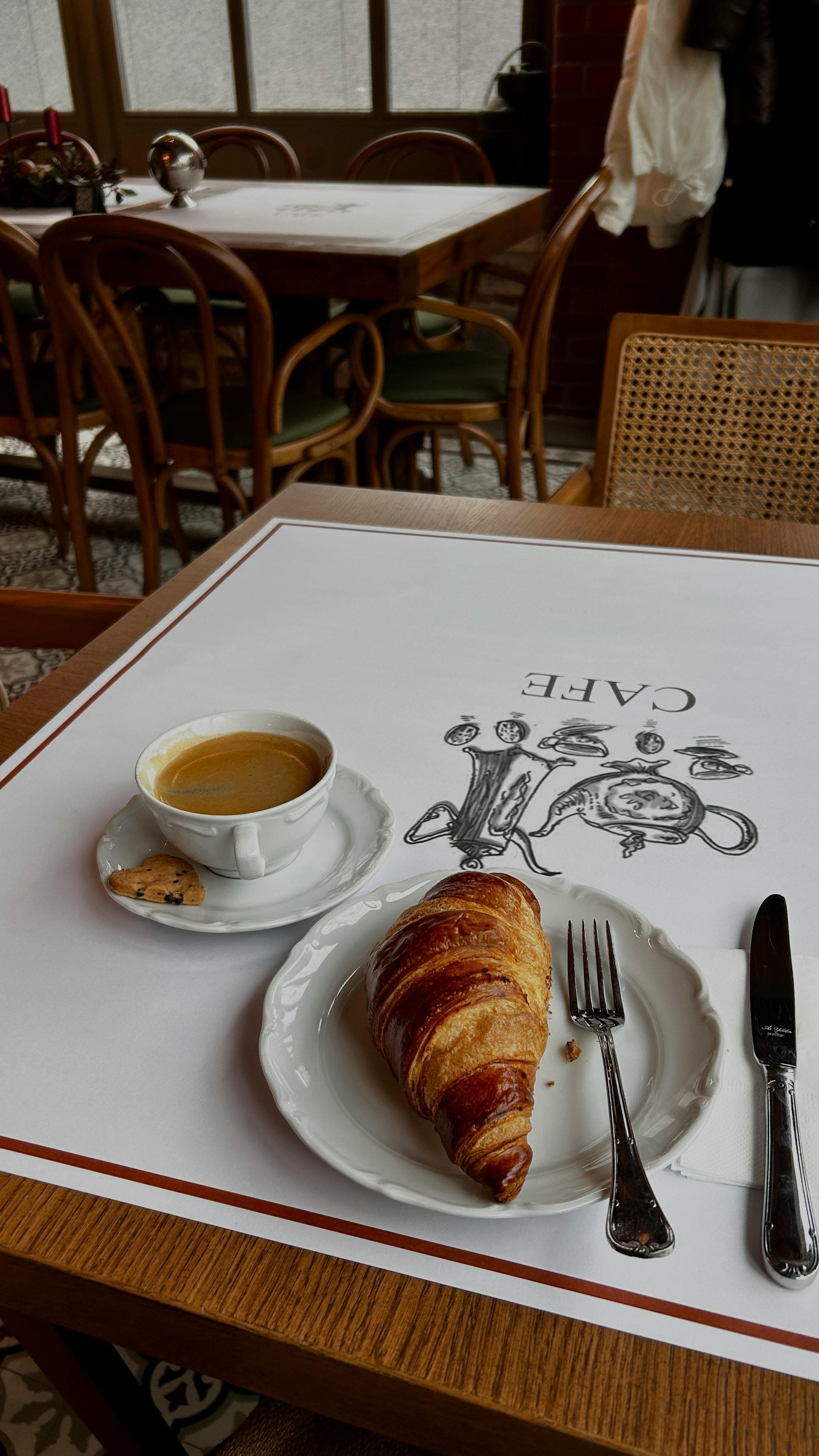 A breakfast plate with croissants and coffee at a café table.